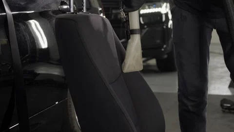 A worker uses a vacuum cleaner to remove dirt from the back of the seat. Video stock 248720641