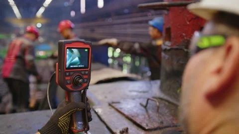 A worker uses a video camera to inspect equipment in a factory. Stock Footage 158954245