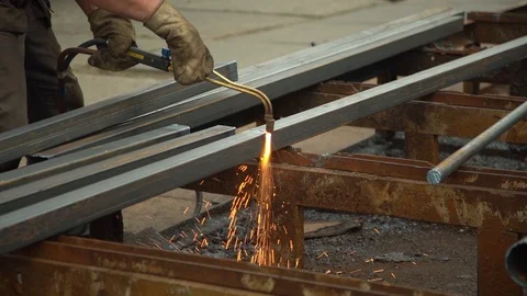 Worker uses a welding machine to cut a metal bar in close-up Stock Footage 114619913