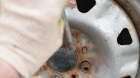 Worker uses a wrench and brush to clean rust from a vehicle wheel. This process 스톡 동영상 337550611