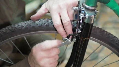 A worker uses a wrench to install rim brakes on a bicycle. Stock Footage 317499339