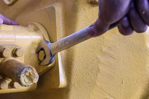 Worker using a 3/4 wrench on a heavy machinery bolt. Stock Photos