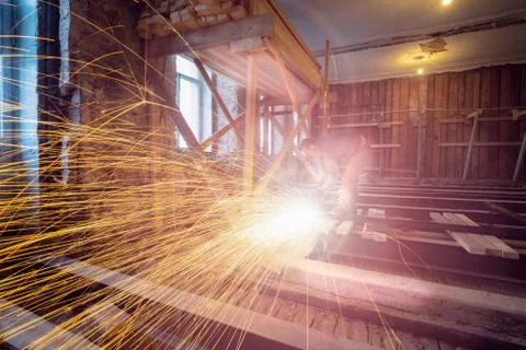 Worker is using angle grinder and fountain of sparks in apartment that is under Stock Photos