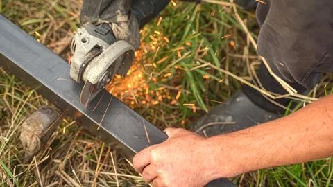 Worker using angle grinder and cutting steel. Smithy manual production Stock Photos