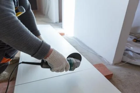 Worker is using angle grinder in apartment that is under construction Stock Photos