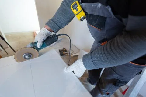 Worker is using angle grinder in apartment that is under construction Stock Photos
