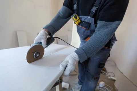Worker is using angle grinder in apartment that is under construction Stock Photos