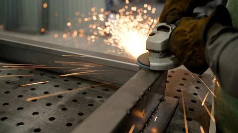 Worker using angle grinder creating sparks on metal surface Stock Photos