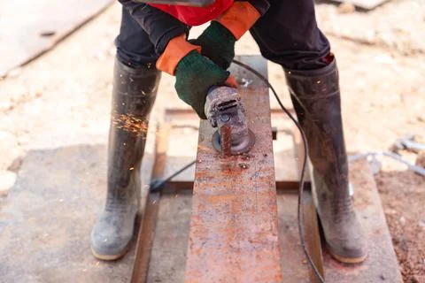 Worker Using Angle Grinder to Cut Steel Beam. Stock Photos