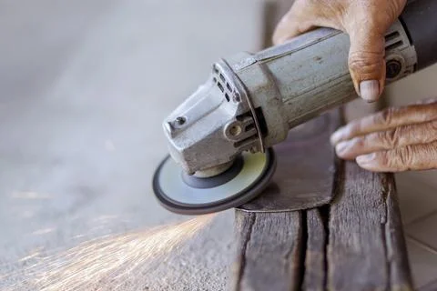 Worker using an angle grinder to cut metal with flying sparks. metalworking.. Stock Photos