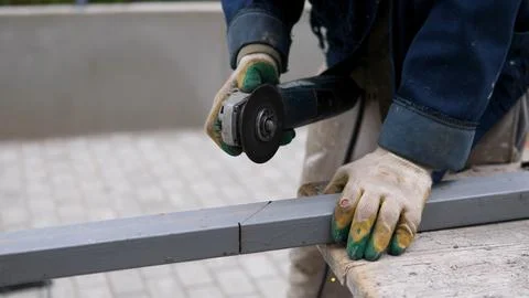 Worker using angle grinder to cut metal beam during construction task with 写真素材