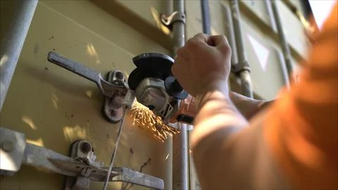 Worker using angle grinder cutting metal lock on shipping container Stock Photos