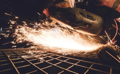 Worker Using Angle Grinder in Factory and throwing sparks. Stock Photos