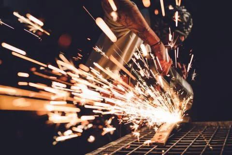 Worker Using Angle Grinder in Factory and throwing sparks. Stock Photos