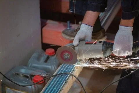 Worker is using angle grinder with fountain of sparks in apartment that is under Stock Photos