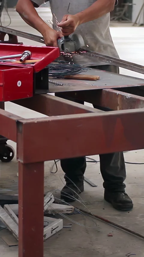 Worker Using Angle Grinder on Metal Bar in Industrial Workshop - Vertical Video Stock Footage 332877796