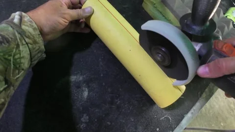 Worker Using Angle Grinder for Precise Longitudinal Cut on PVC Pipe Stock Footage 337530835