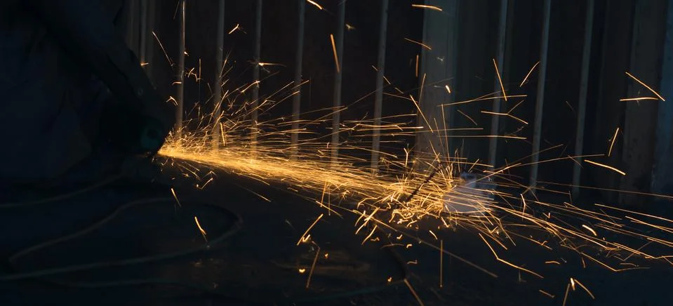 A worker using angle grinder in a workshop with sharp orange sparks Stock Photos