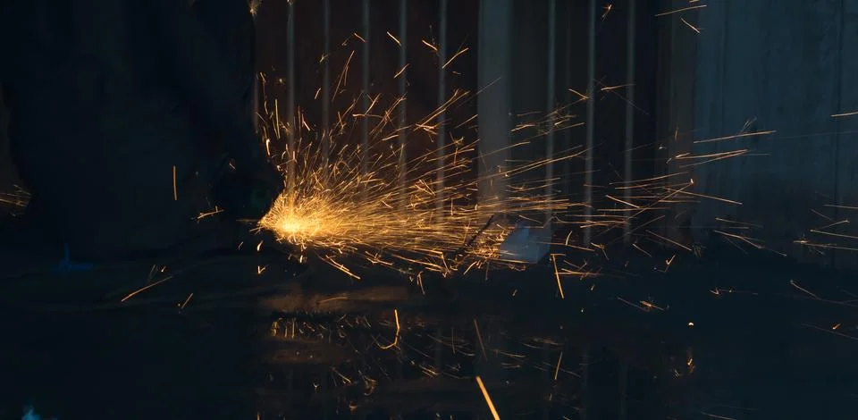 A worker using angle grinder in a workshop with sharp orange sparks Stock Photos