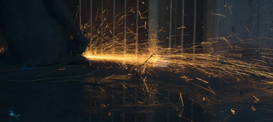 A worker using angle grinder in a workshop with sharp orange sparks Stock Photos