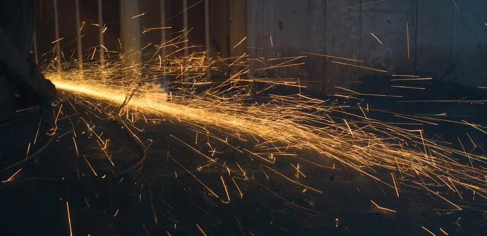 A worker using angle grinder in a workshop with sharp orange sparks Stock Photos