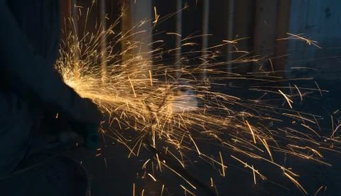 A worker using angle grinder in a workshop with sharp orange sparks Stock Photos