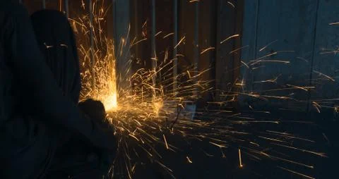 A worker using angle grinder in a workshop with sharp orange sparks Stock Photos