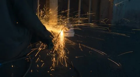 A worker using angle grinder in a workshop with sharp orange sparks Stock Photos