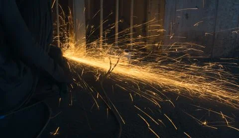 A worker using angle grinder in a workshop with sharp orange sparks Stock Photos