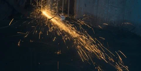 A worker using angle grinder in a workshop with sharp orange sparks Stock Photos