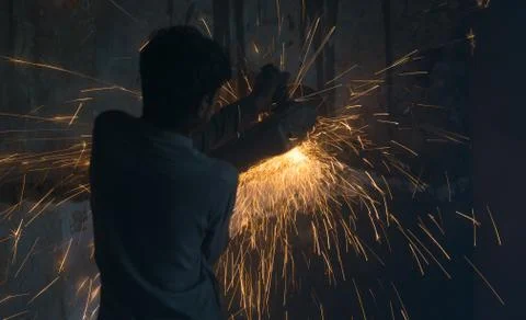 A worker using angle grinder in a workshop with sharp orange sparks Stock Photos