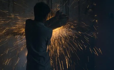 A worker using angle grinder in a workshop with sharp orange sparks Stock Photos