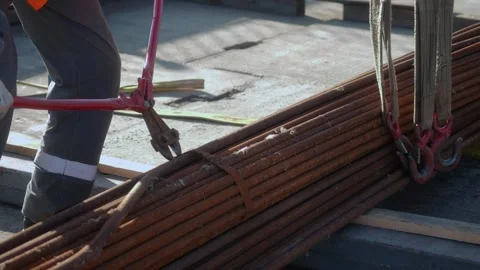 Worker using bolt cutter on steel rods at industrial construction site, cap.. Stock Footage 284960437