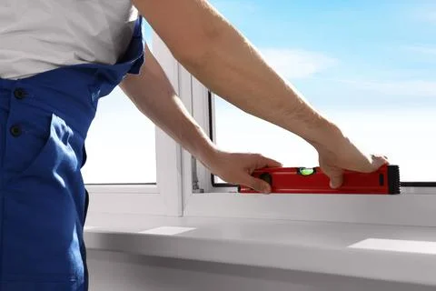 Worker using bubble level after plastic window installation indoors, closeup Stock Photos