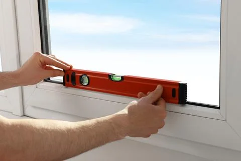 Worker using bubble level after plastic window installation indoors, closeup Stock Photos