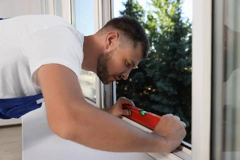 Worker using bubble level after plastic window installation indoors Stock Photos