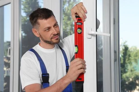 Worker using bubble level after plastic window installation indoors Stock Photos