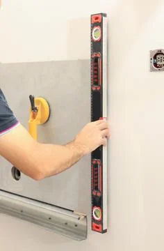 Worker using building level for tiles installation on wall indoors, closeup Fotos de archivo