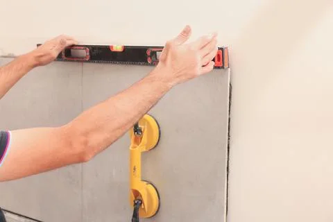 Worker using building level for tiles installation on wall indoors, closeup Fotos de archivo