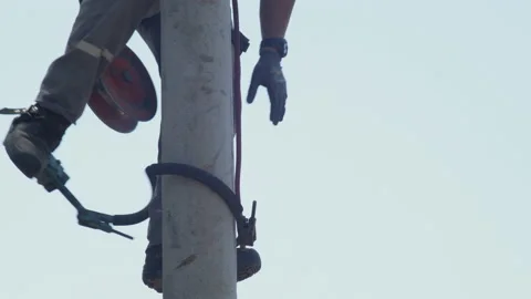 Worker using climbing boots and belt equipment to go down from pole Stock Footage 157376528