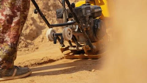 Worker using a compacting machine on sandy ground Stock Photos