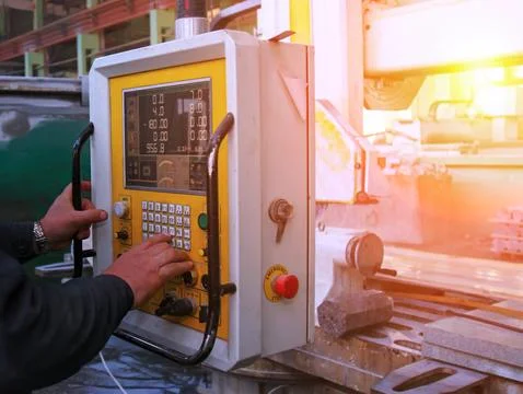 A worker is using a control panel to operate heavy machinery in a factory. Th Foto stock