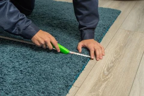 Worker using cutter while installing new carpet flooring in room. Carpet rest Foto stock