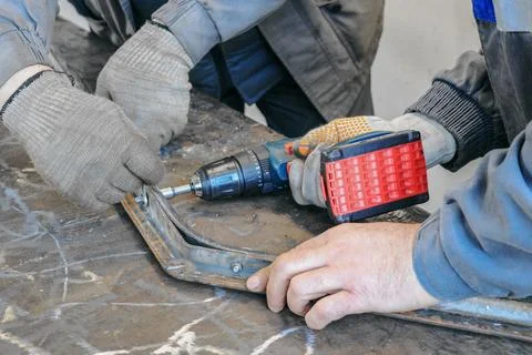 Worker using a drill to cut a metal profile on a construction site Stockfoto's