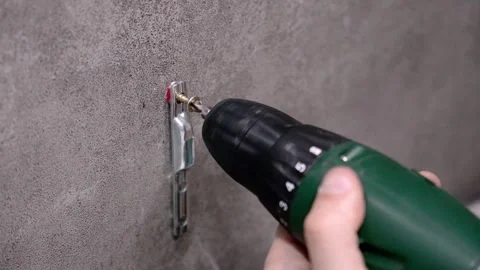 Worker using drill to screw metal bracket on concrete wall Stock Footage 304118209