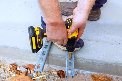 Worker using drill to secure metal brackets on concrete surface Stock Photos