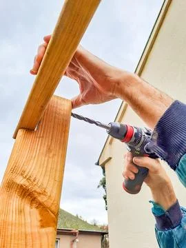 Worker using drill working on construction of wood frame house, gazebo Stock Photos