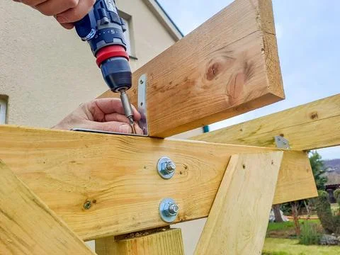 Worker using drill working on construction of wood frame house, gazebo Stock Photos