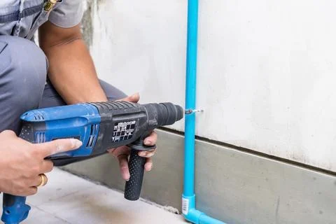 Worker using a drilling power tool on construction site and drills holes in.. Stock Photos