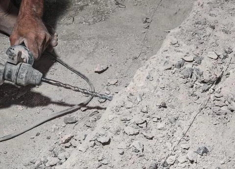 Worker Using Electric Drill on Concrete Surface During Construction Work Stock Photos